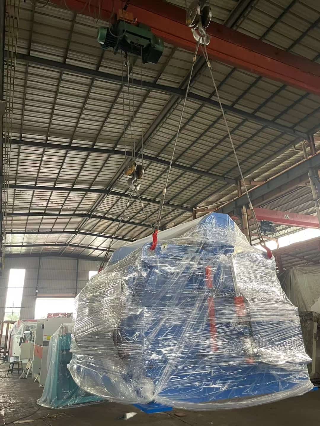 Step 1: Machine wrapped in protective film being lifted by crane